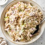 Cottage cheese chicken salad served in a cream bowl with a spoon. There is a small bowl with salt and pepper next to it.