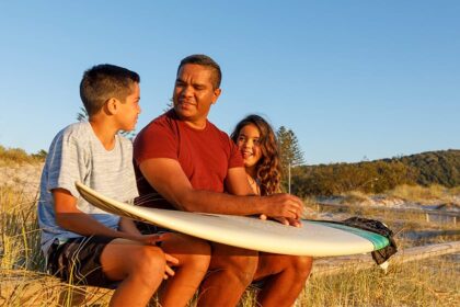 dad and kids with a surf board