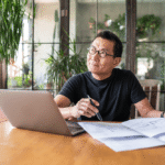 mature asian man with laptop thinking
