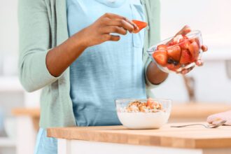 woman adding fruit to yogurt