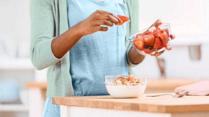 woman adding fruit to yogurt