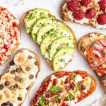 Assorted cottage cheese toast ideas topped with avocado, smoked salmon, pizza marinara, raspberries, banana with chocolate chips, and berry jam.